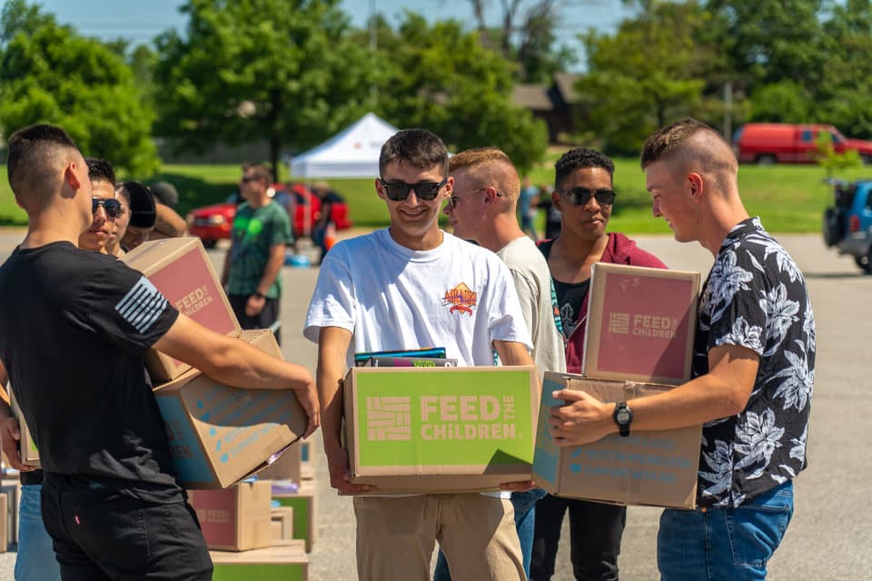 Un grupo de hombres cargando cajas en un evento al aire libre