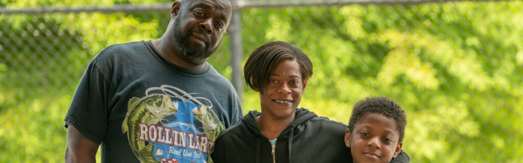 Una familia al aire libre delante de una valla y árboles
