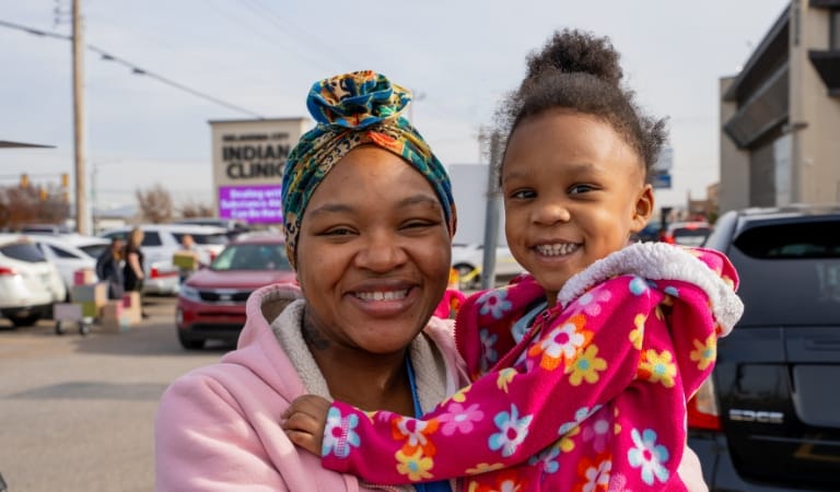 A mother and daughter smiling at an outdoor event