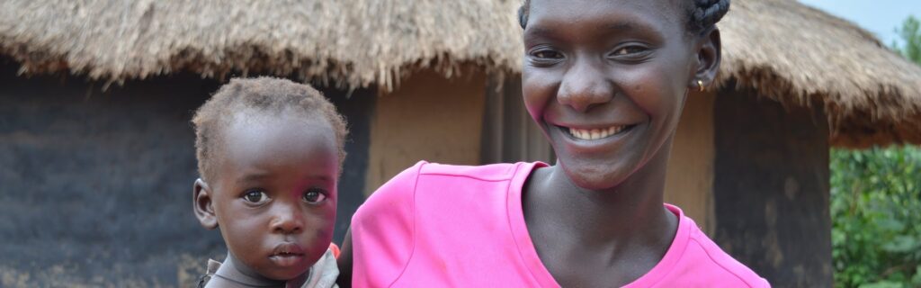 Una madre con su hijo en brazos sonriendo al aire libre