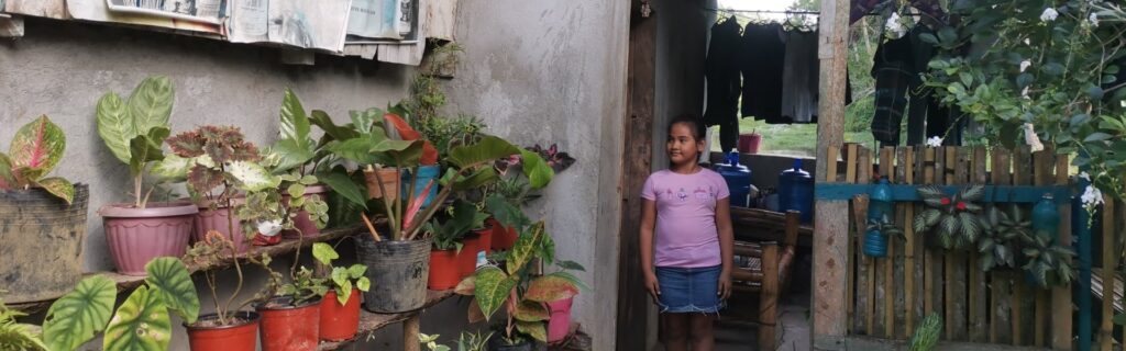 Un niño frente a una casa con plantas