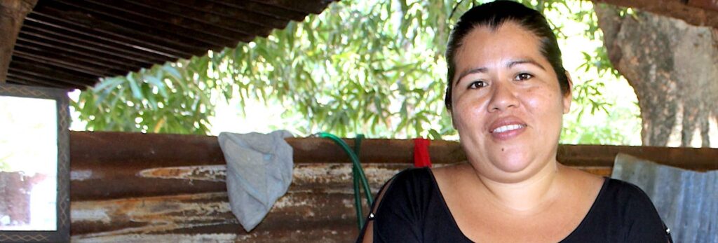 Una mujer sonríe sentada en una estructura al aire libre