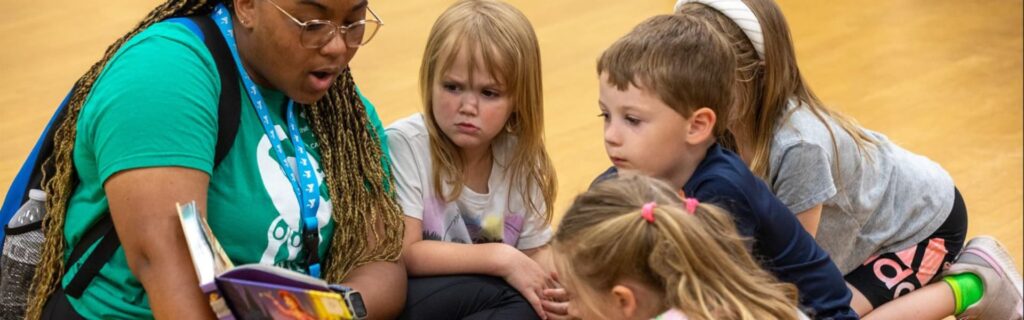 Un profesor y unos niños leyendo un libro en un gimnasio