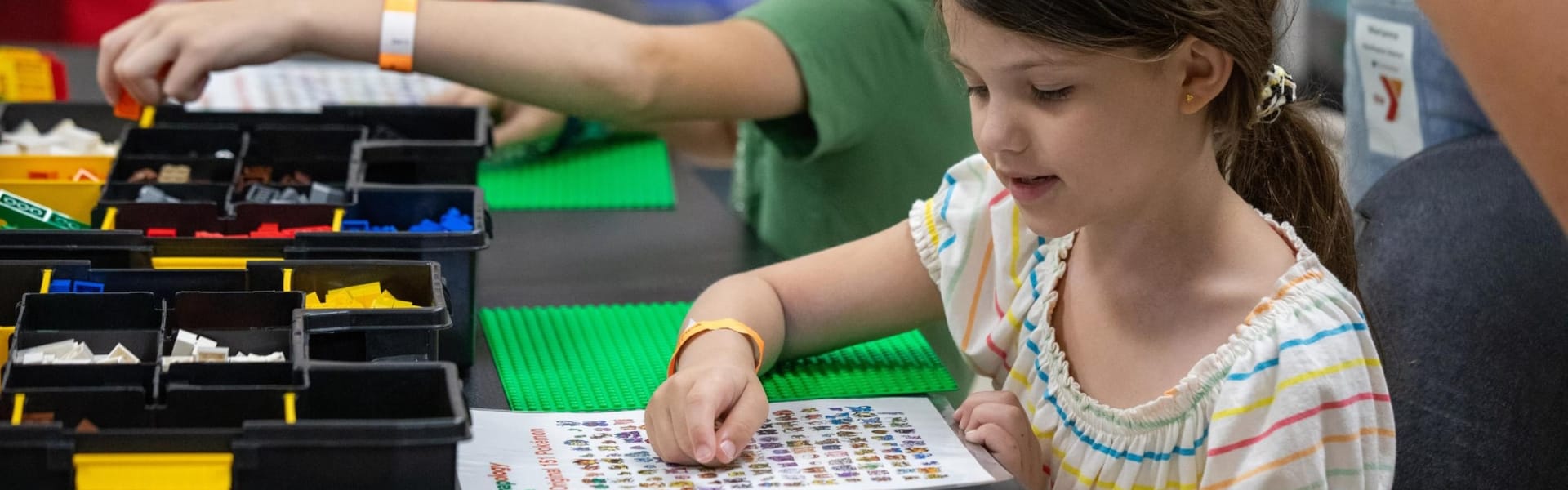 Una niña sentada a la mesa del colegio haciendo manualidades