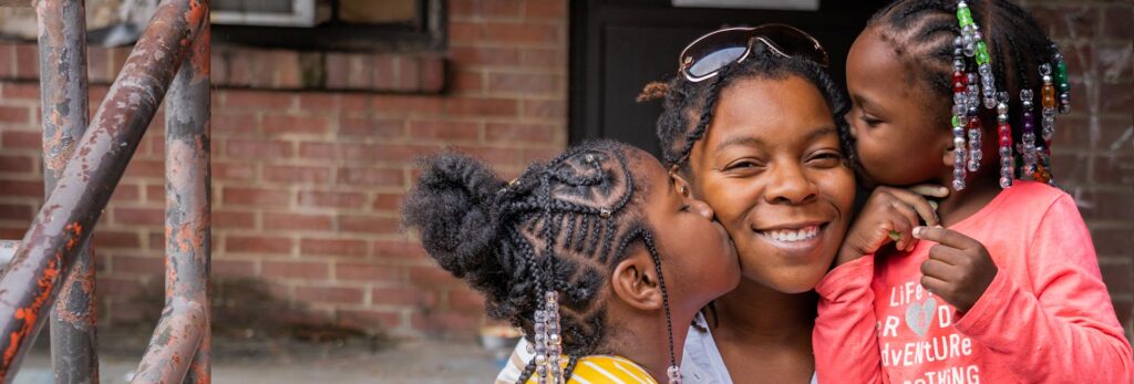 Una madre con sus dos hijas sonriendo al aire libre