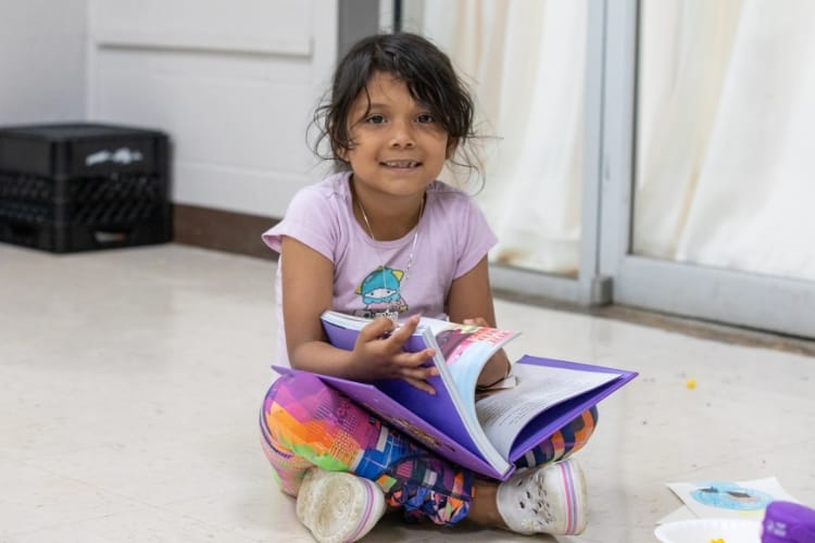 A child sitting on the floor reading a book