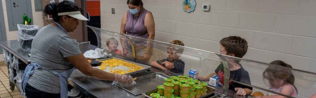 Niños en la cola de una cafetería escolar recibiendo comida