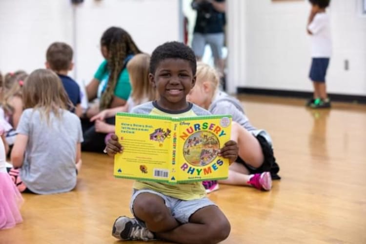 A boy reading a book in a school gym