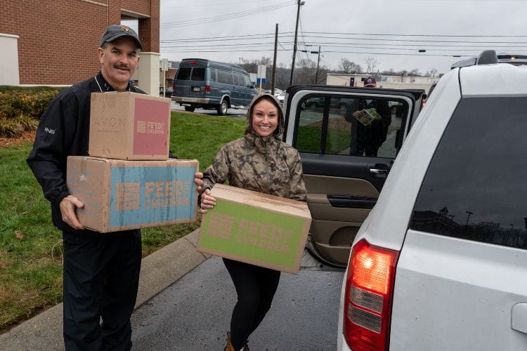 Two volunteers loading boxes into a car