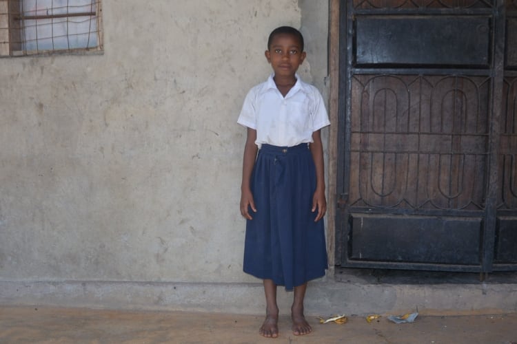 A girl standing against a wall outdoors