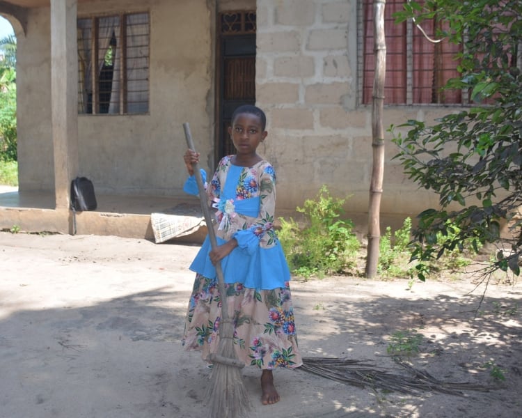 A girl sweeping the ground outdoors