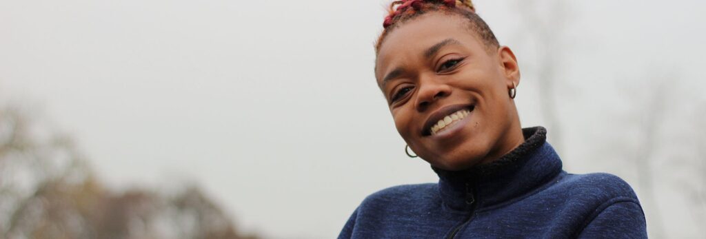 Una mujer sonríe de pie al aire libre