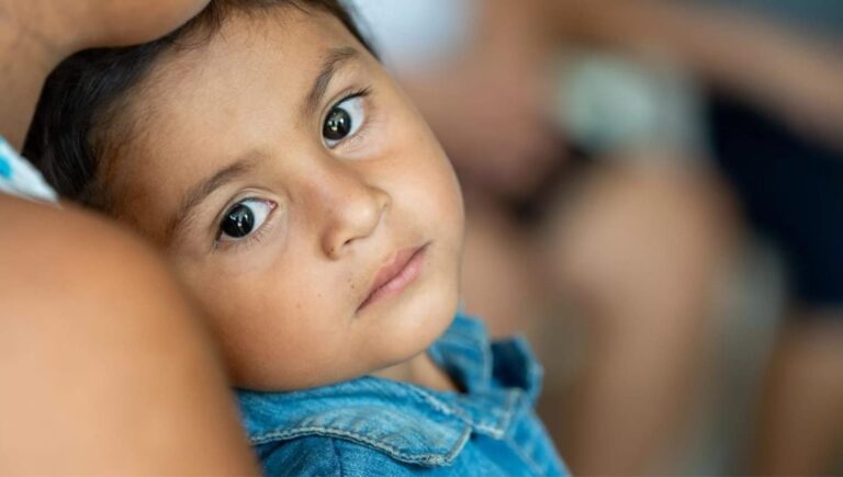 Un niño apoyado en un adulto