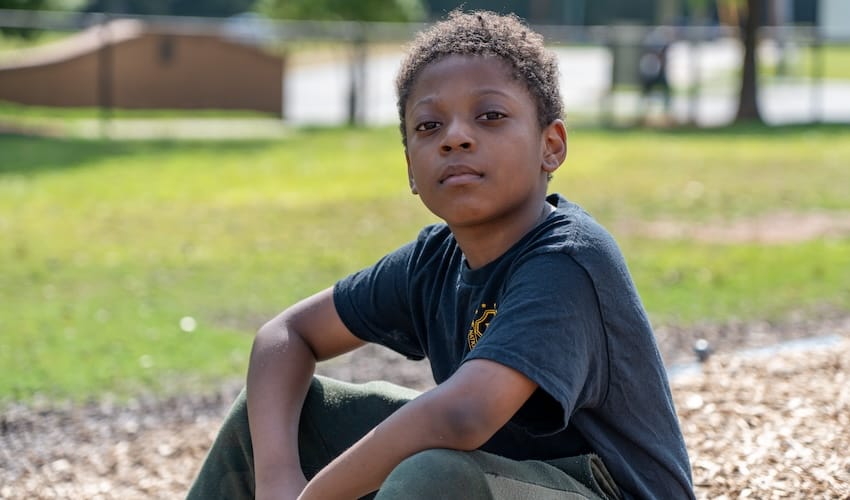 A boy sitting outdoors in a field