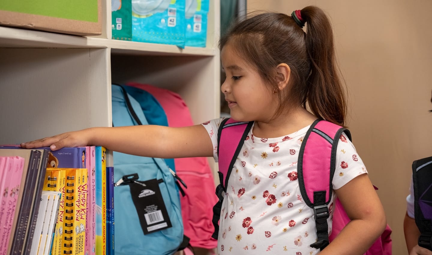 Una niña con la mano sobre los libros en una escuela.