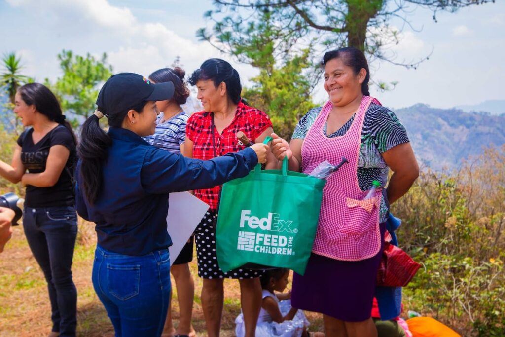 A woman handing out bags to individuals in an outdoor environment