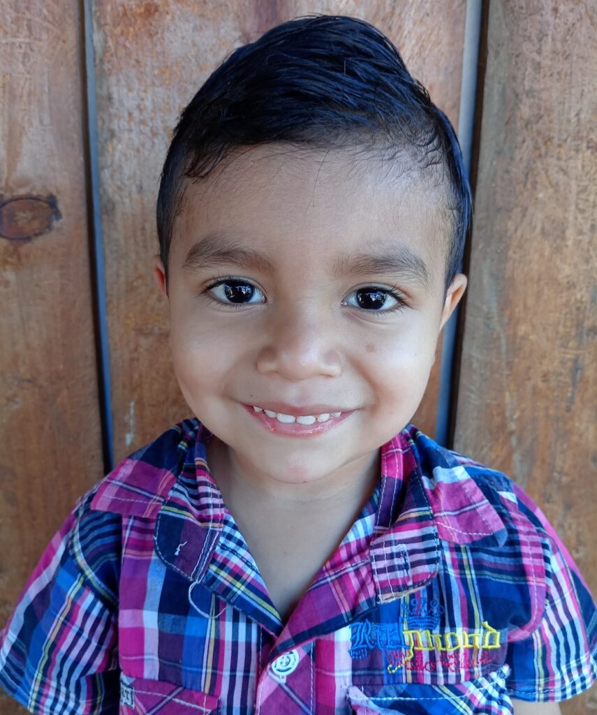 Un niño sonríe delante de una valla.