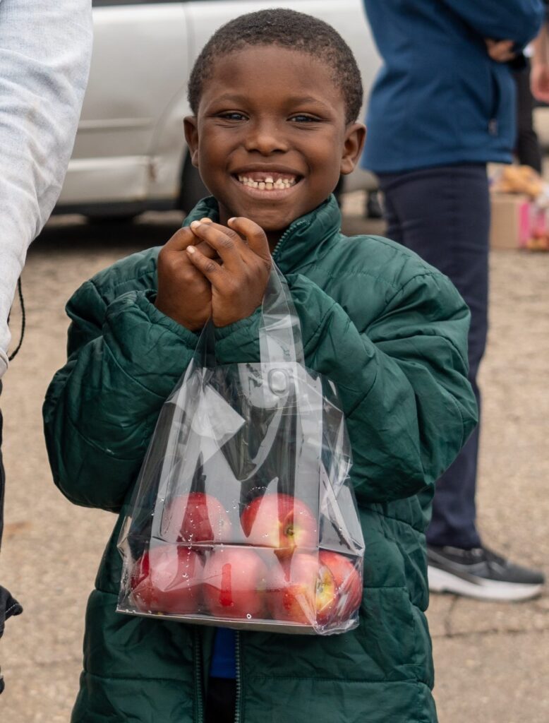 Un niño con una bolsa de manzanas en un evento al aire libre.