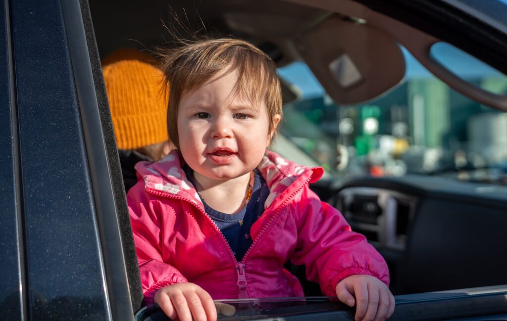 A toddler looking out of a car window.
