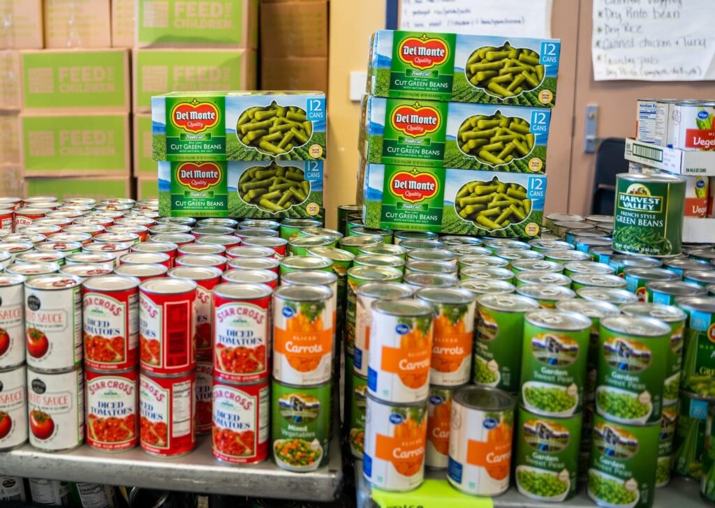 Un montón de latas apiladas en una mesa frente a unas cajas.