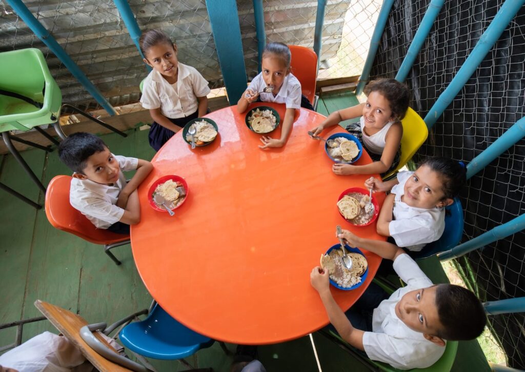 A group of children eating at a circular table in south america.