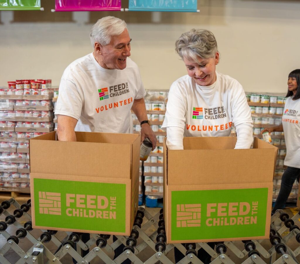 Dos voluntarios llenan cajas con alimentos.