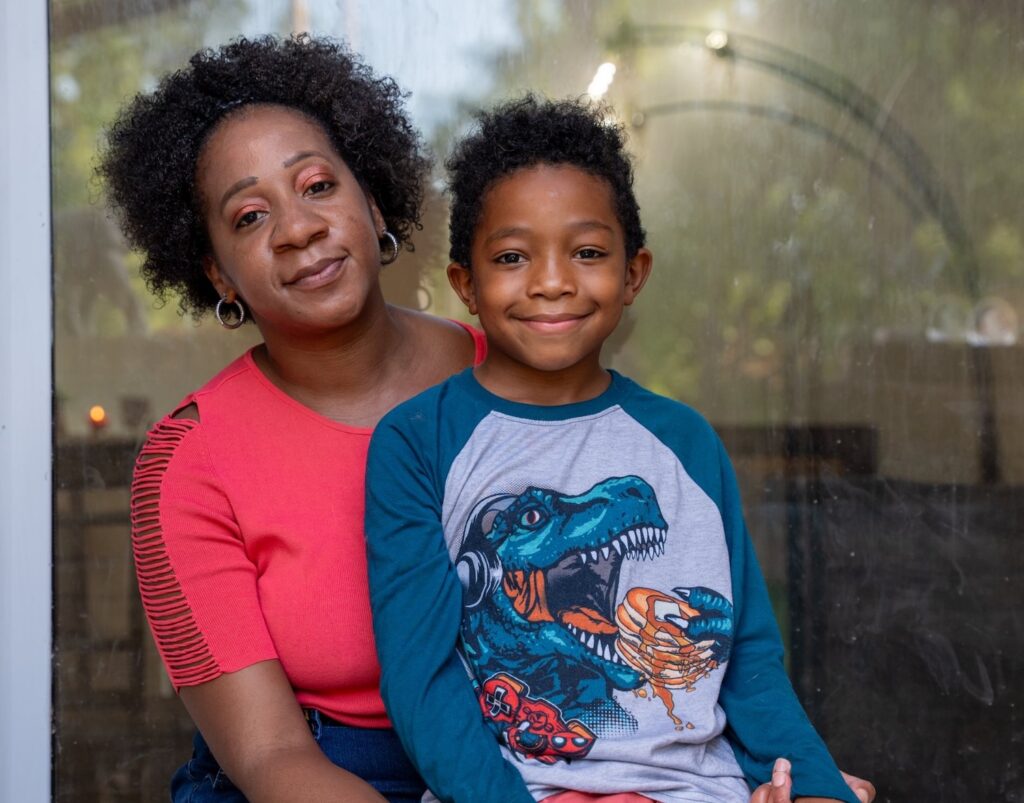 Rose and her son sitting on a chair posing for a photo.