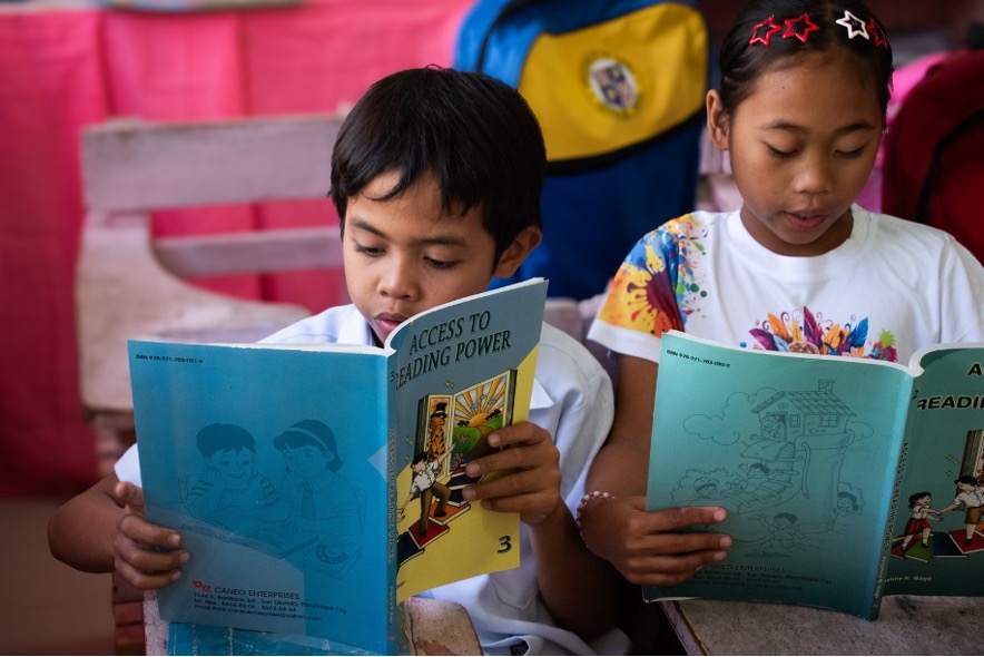 A boy and girl reading books in school.