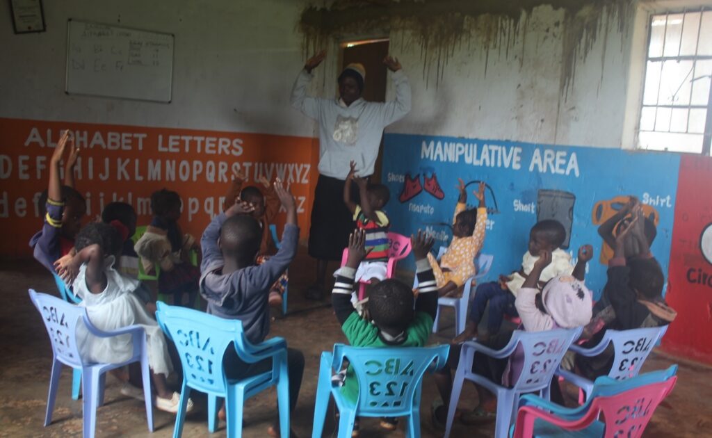 A group of children in a Malawi classroom raising their hands.
