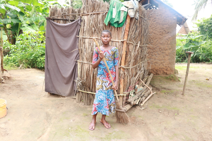 Beatrice standing with a broom outside a house