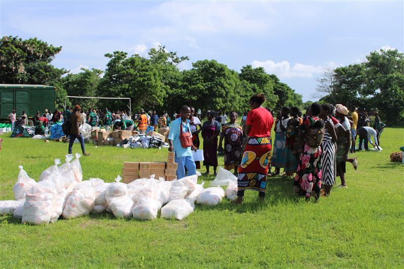 A group of aid workers in a field with bags and boxes of supplies.