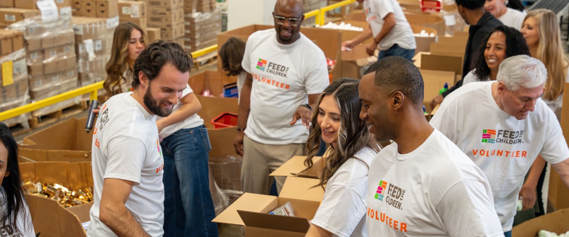 Volunteers filling a row of boxes with supplies.