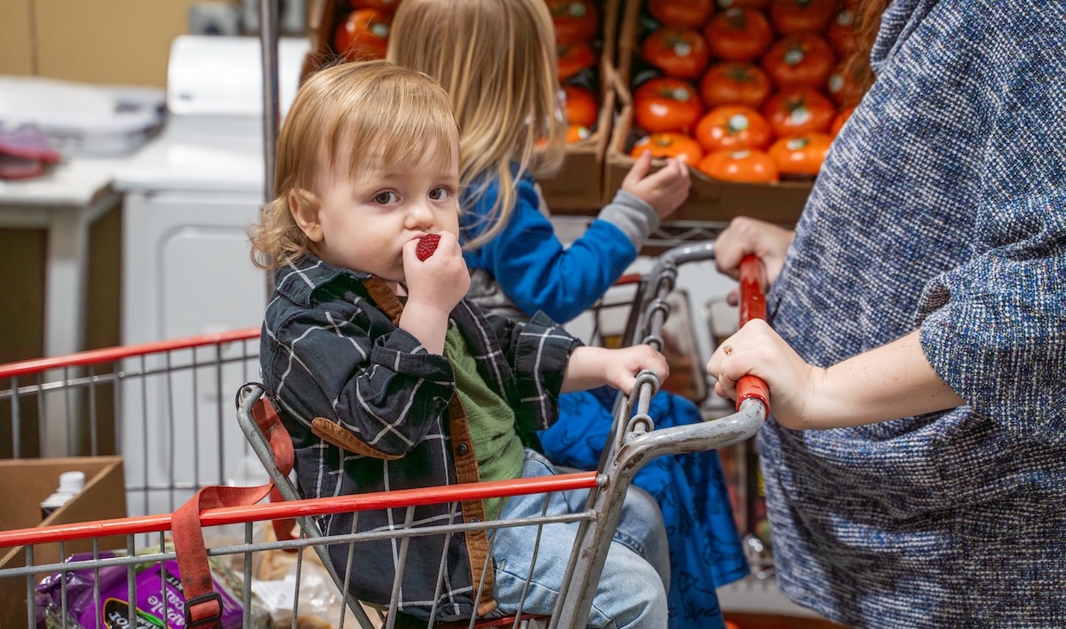 Niños montados en un carrito de supermercado.