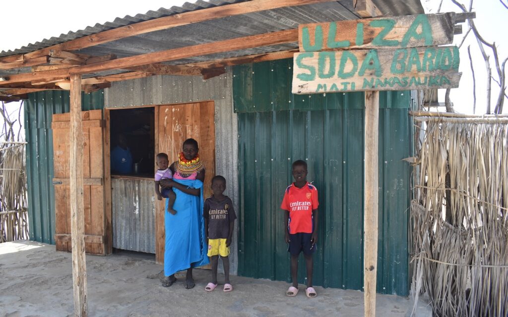 Everline and her children standing next to her shop building.