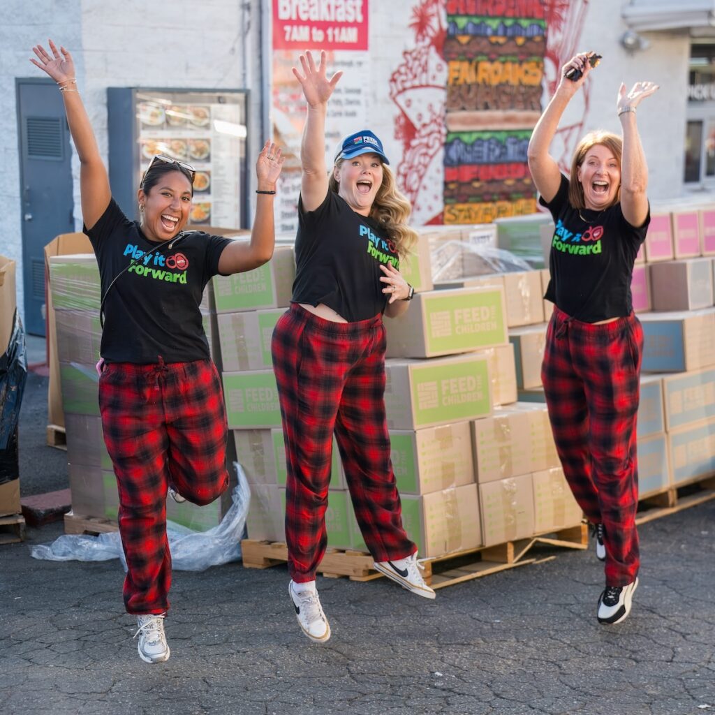 A group of three women jumping in pajama's at an outdoor event.